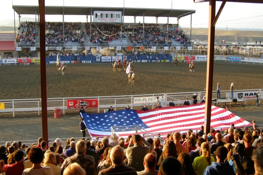 CODY, WYOMING - July 23, 2014: Arena of Cody Stampede Park. Cody - Capitol Rodeo. Solemn opening of the rodeo with the lifting of the American flag.
