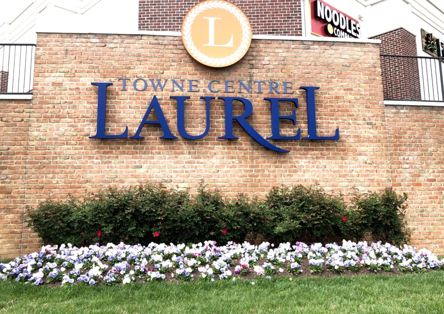 Laurel, Maryland/USA-April 25, 2019: Laurel Towne Center sign with a brick background decorated with foliage on the bottom.