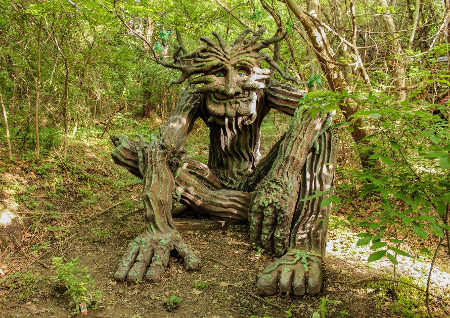 The woodland greenman sculpture setting in dappled forest with sun and shadow at Muskogee Oklahoma USA.
