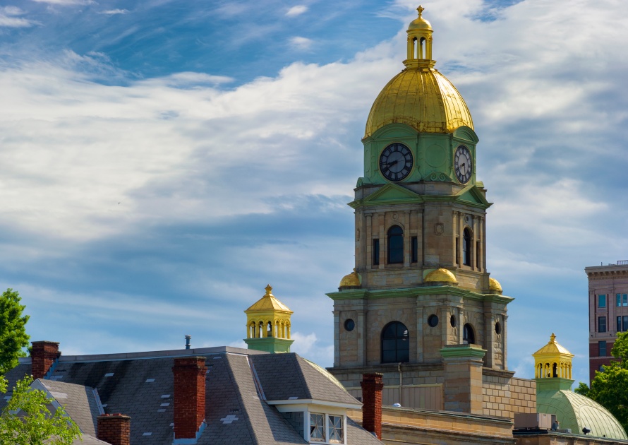 Huntington, West Virginia, USA -June 27,2018: Clock and golden dome of Huntington West Virginia, Cabell County Courthouse rises above the rooftops of other buildings against a cloudy sky.