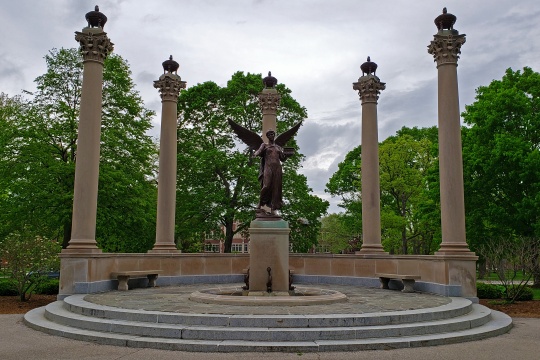 Muncie, Indiana / United States - May10, 2019 Ball State University Beneficence Statue with trees and overcast sky.