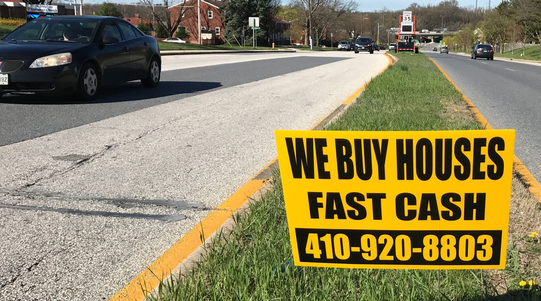 We Buy Houses Sign in the middle of the street